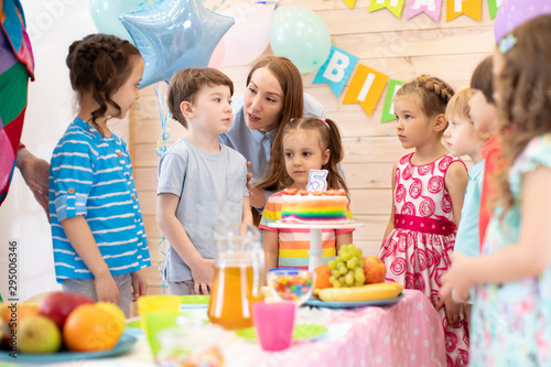 Group of adorable kids  birtday boy and his mom gathered around festive table. Birthday party for preschoolers