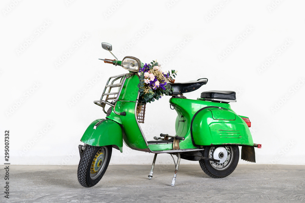 Green vintage scooter with a bouquet of flowers in basket