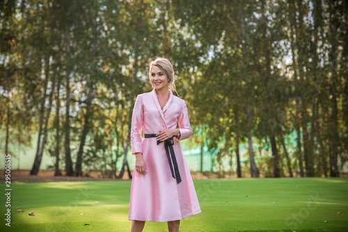 Fashionable concept. Romantic lady in pink trench outdoors 