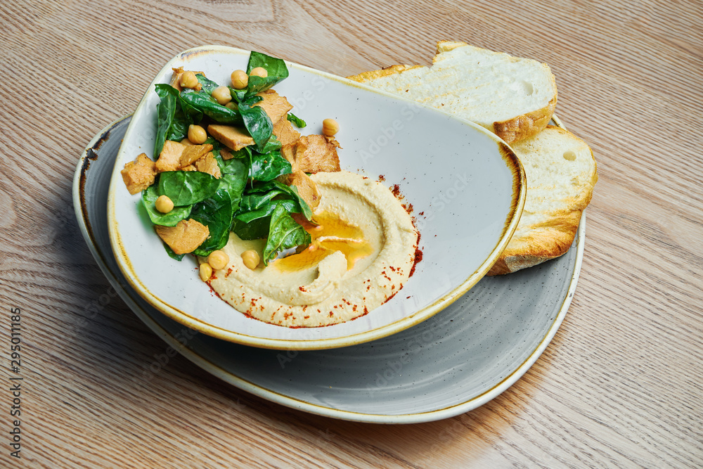 Traditional chickpea hummus in bowl with salad, bread, turkey. Israeli cuisine. Snack. Wooden background