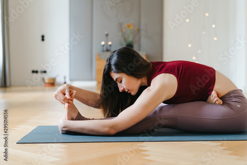 Junge Frau liegt auf Matte und macht Yoga-Übungen