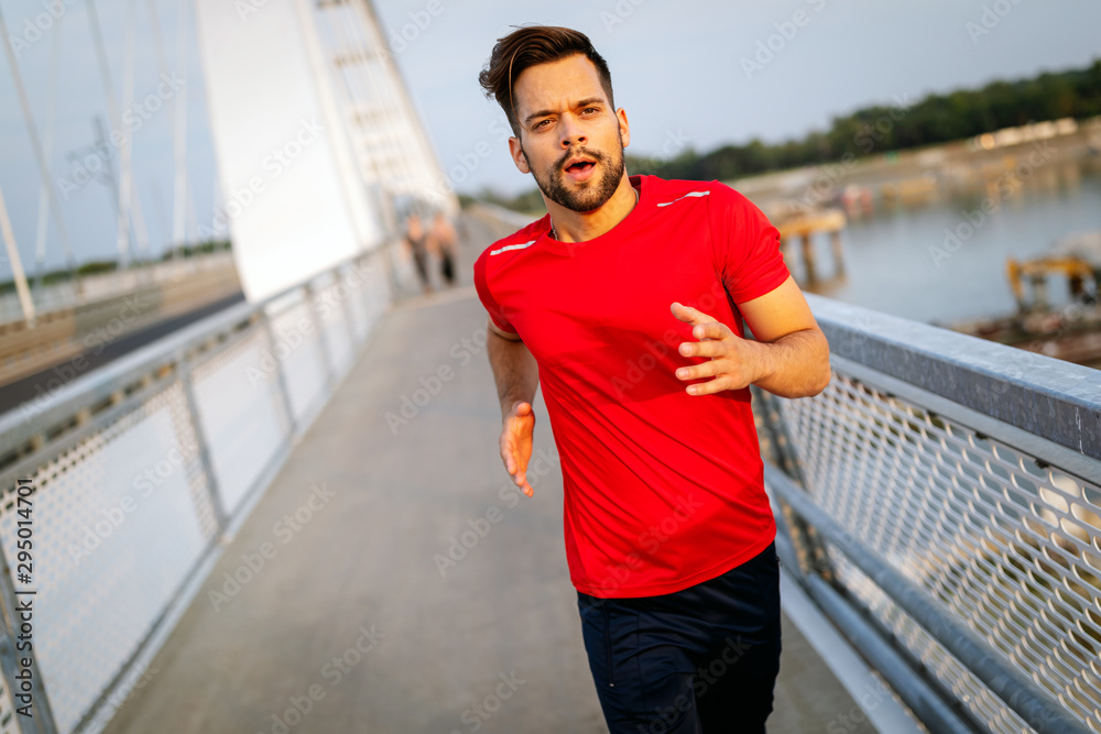 Fototapeta premium Handsome young man running across the bridge.