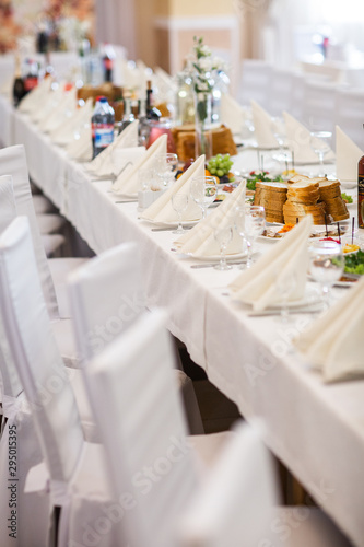 Tables setting at a luxury wedding. Table for guests. Dishes and drinks. Floral decorating, white chairs and table. Wedding table preparation. top view. vertical photo © MONIUK ANDRII