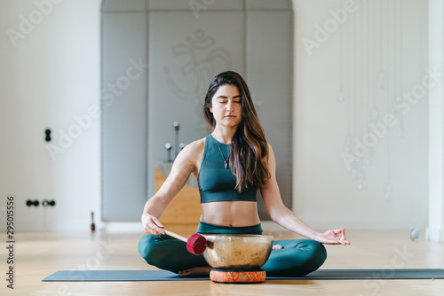 Sportliche junge Frau beim Yoga mit einer Klangschale