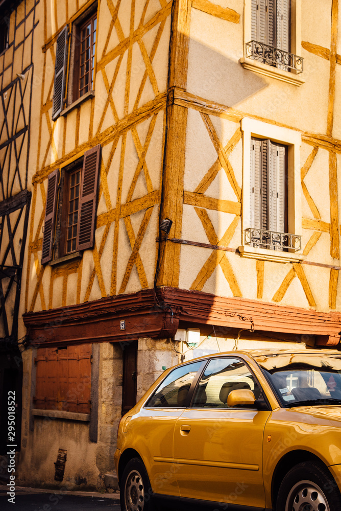 une voiture jaune garée devant un vieil immeuble à colombage