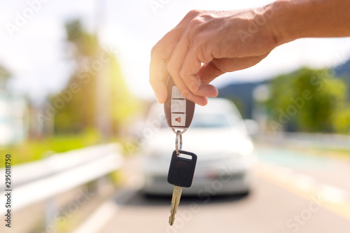 Hand man holding car keys and blur car in background. © AKGK Studio