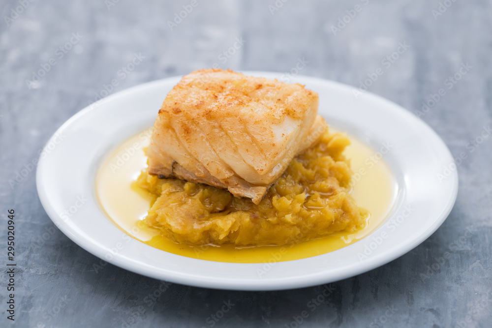 cod fish with mashed potato and olive oil on white dish