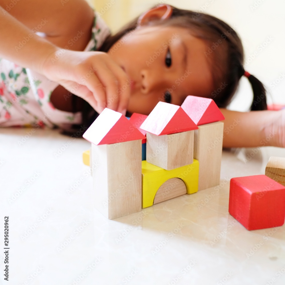 A little girl playing with colorful wooden blocks in the room. Child girl building house. A little girl playing with colorful wooden blocks in the room. Child girl building house.
