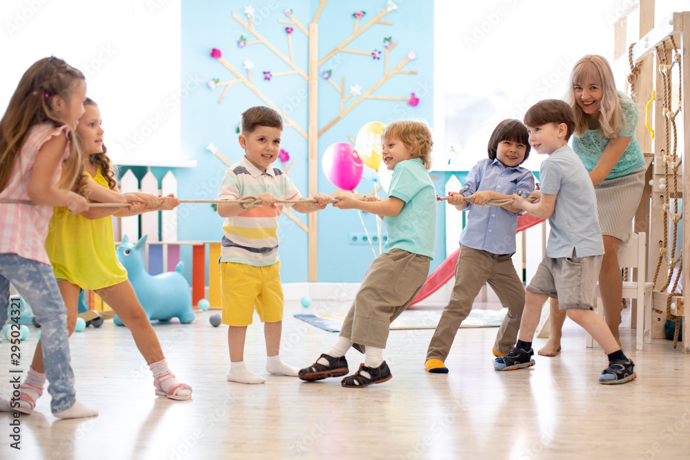 Fototapeta premium group of preschool children play and pull rope together in competition