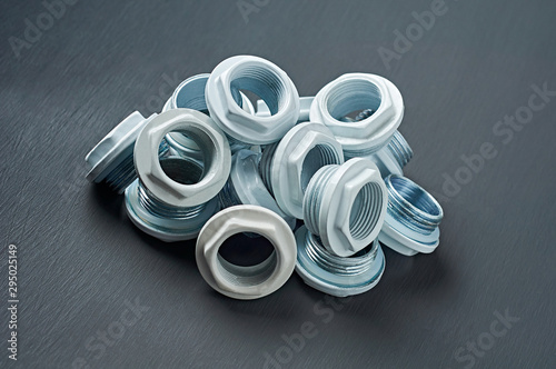 One heap of many new white nuts with double thread for bimetallic or aluminum radiator for heat room lies on dark concrete table in workshop. Close-up