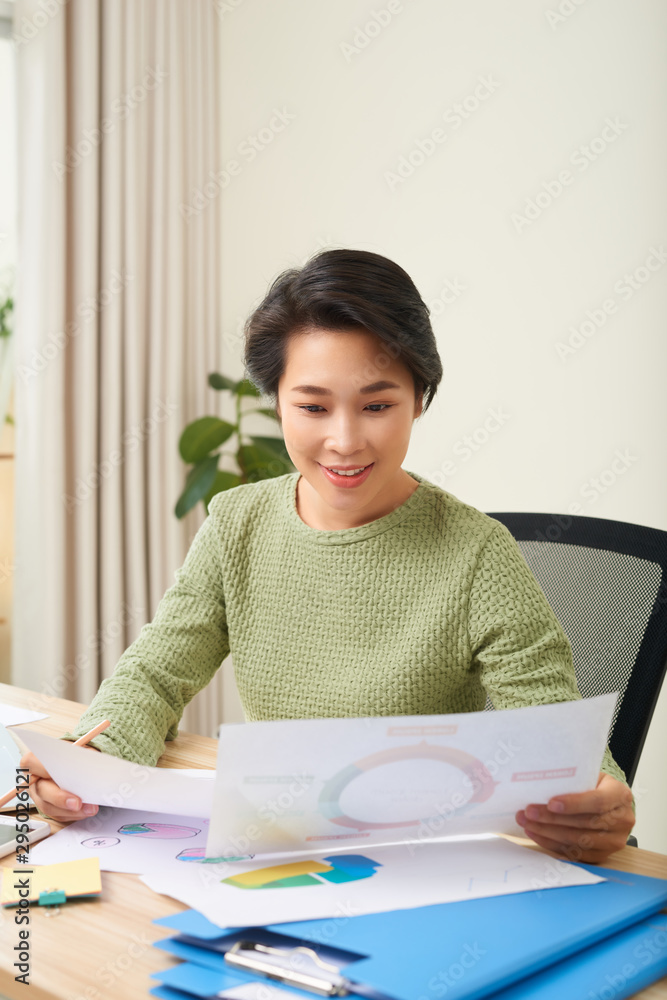 Concentrated woman sit at table reading documents and taking note Concentrated woman sit at table reading documents and taking note