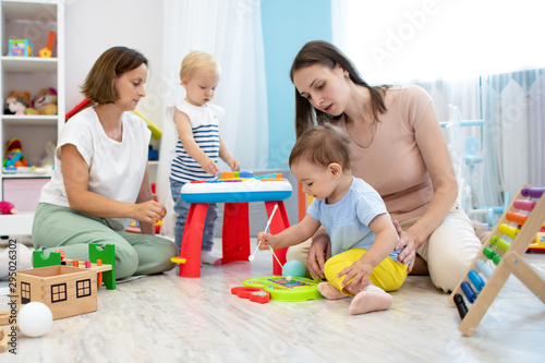 Kindergarten teacher playing with little kids in nursery. Developmental toys for preschool.