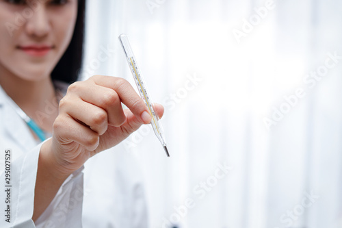 Female doctor holding a thermometer. Is a measure of body temperature to see if it is normal or has a fever