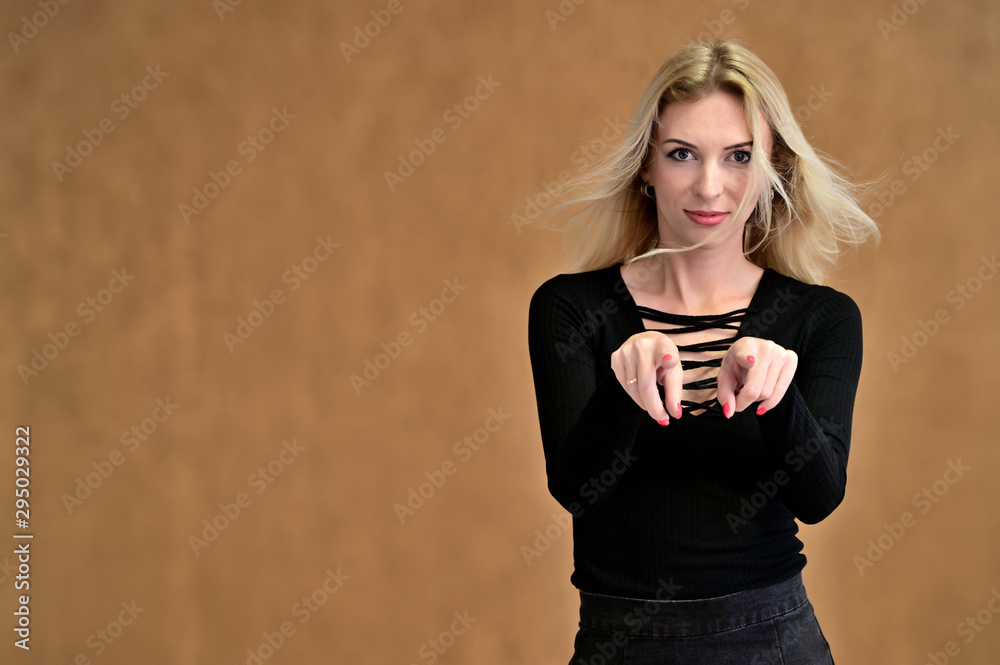 Studio portrait of a pretty blonde student girl with long hair in a black blouse on a beige background. Smiling at camera with emotions in various poses. Studio portrait of a pretty blonde student girl with long hair in a black blouse on a beige background. Smiling at camera with emotions in various poses.