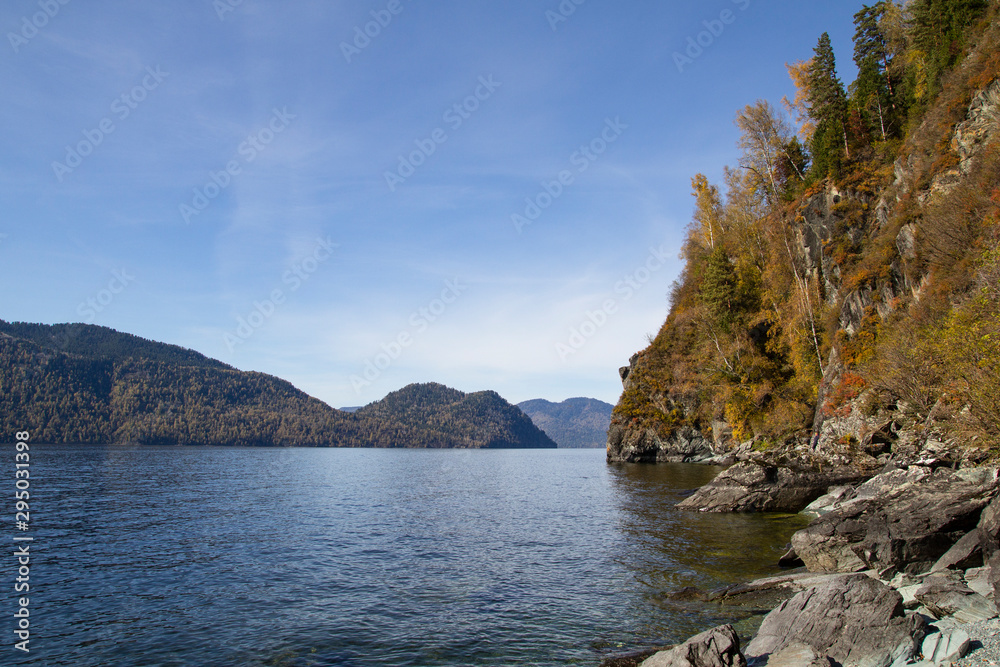 Autumn landscape: shore of a mountain lake on a sunny day