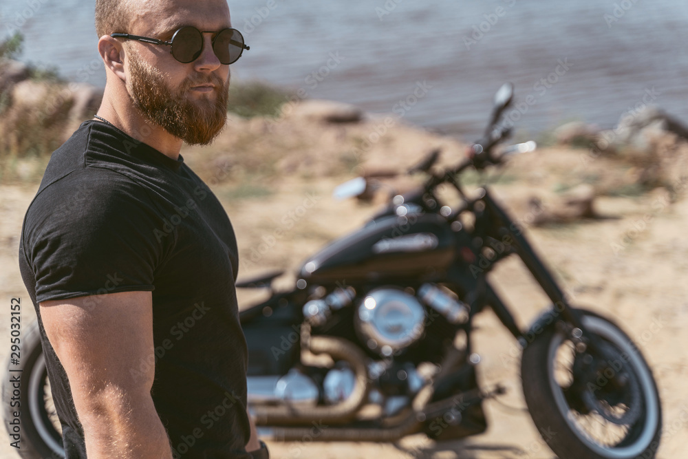 Portrait of an attractive bearded man standing in front of his bike