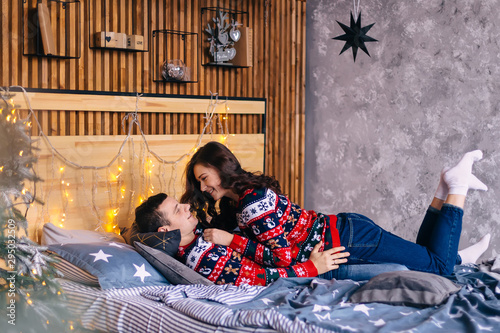 couple in love in beautiful sweaters lie on bed. cozy room and C