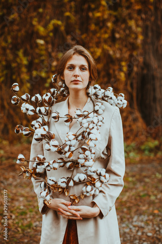 Stylish tender woman with cotton flowers around her. Boho style fashion.