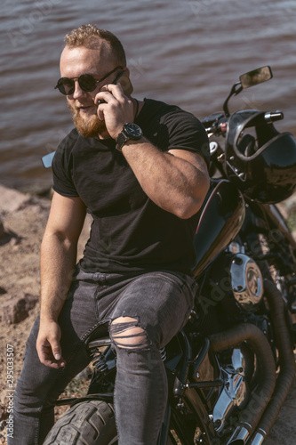 Confident bearded man lying on bike talking on the phone