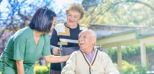 Female doctor reassuring elderly retired people in the hospital garden