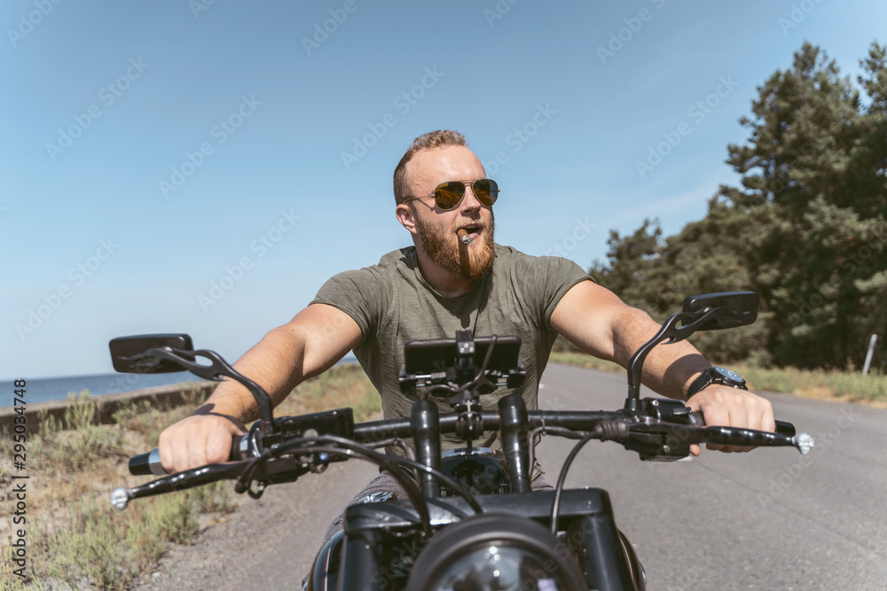 Handsome bearded man with sigar riding his motorcycle