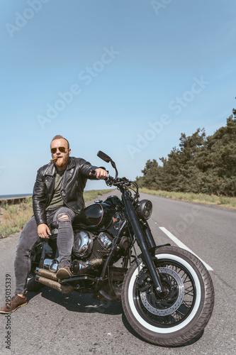 Sexy bearded man in leather jacket sitting on his bike