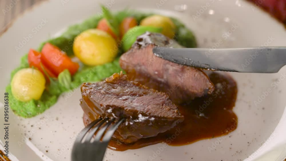 Man eating delicious meat dish cutting with knife and fork in restaurant Man eating delicious meat dish cutting with knife and fork in restaurant