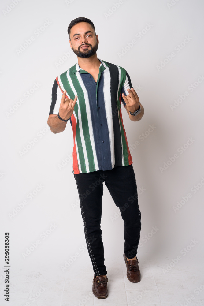 Full body shot of young bearded Indian man with rock gesture Full body shot of young bearded Indian man with rock gesture