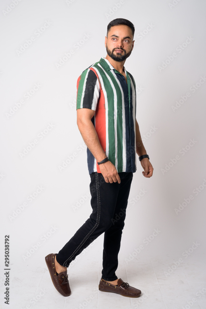 Full body shot of young bearded Indian man thinking Full body shot of young bearded Indian man thinking
