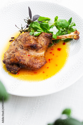 Obraz na płótnie Roast duck leg with mango sauce, salade and chilli pepper on white plate, closeup. Vertical view from above, top shot. White background. w salonie