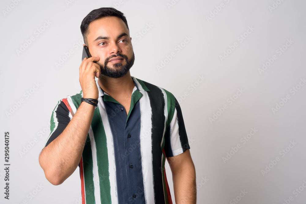 Portrait of young handsome bearded Indian man talking on the phone Portrait of young handsome bearded Indian man talking on the phone