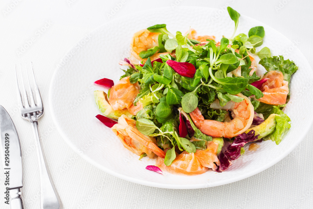 Healthy Salad. Recipe for fresh seafood. Grilled shrimps, prawns, fresh salad lettuce and avocado slices. Healthy Eating. White background. Horizontal photo.