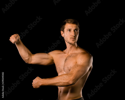 Muscular model young man on isolated black background. Sport workout bodybuilding Fitness concept. Strong bodybuilder brawny posing.