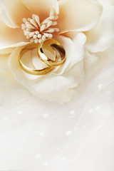 wedding rings with flowers and bridal dress folds