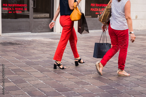 des femmes marchant dans la rue. Des femmes avec un pantalon rouge. Des femmes avec des sacs de shopping.