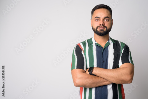 Portrait of young handsome bearded Indian man with arms crossed
