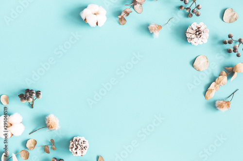 Winter composition. Dried leaves, cotton flowers, berries, pine cones on blue background. Winter, christmas concept. Flat lay, top view, copy space