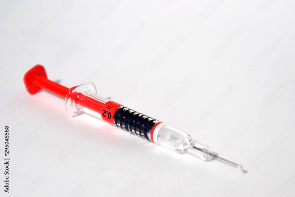 Red bright syringe lying on white background, diabetes, blood thinning or vaccination concept Red bright syringe lying on white background, diabetes, blood thinning or vaccination concept