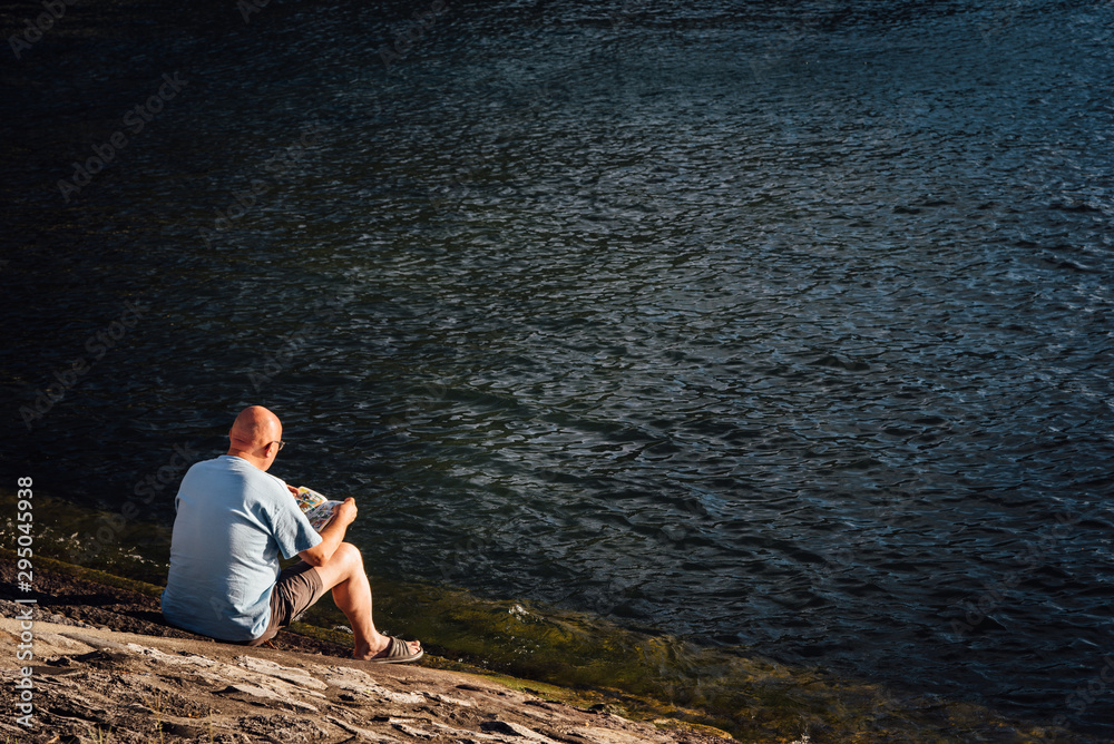 un homme lisant au bord de l'eau un homme lisant au bord de l'eau