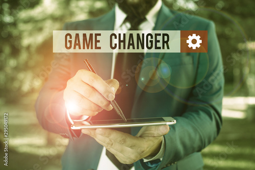 Text sign showing Game Changer. Business photo showcasing way that effects a major shift in the current analysisner of doing Businessman in blue suite stands with mobile phone in hands photo