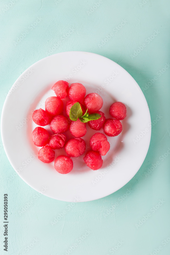Watermelon balls in a white plate on a turquoise background. Watermelon. Dessert with watermelon Watermelon balls in a white plate on a turquoise background. Watermelon. Dessert with watermelon