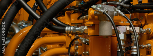 Banner with close up view of hydraulic pipes of heavy industry machine. Low key.