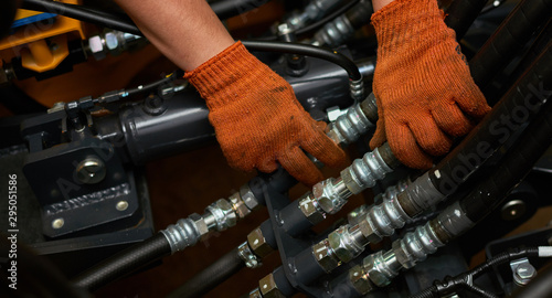 Low key photo of hydraulic pipes maintenance on heavy industry machine.
