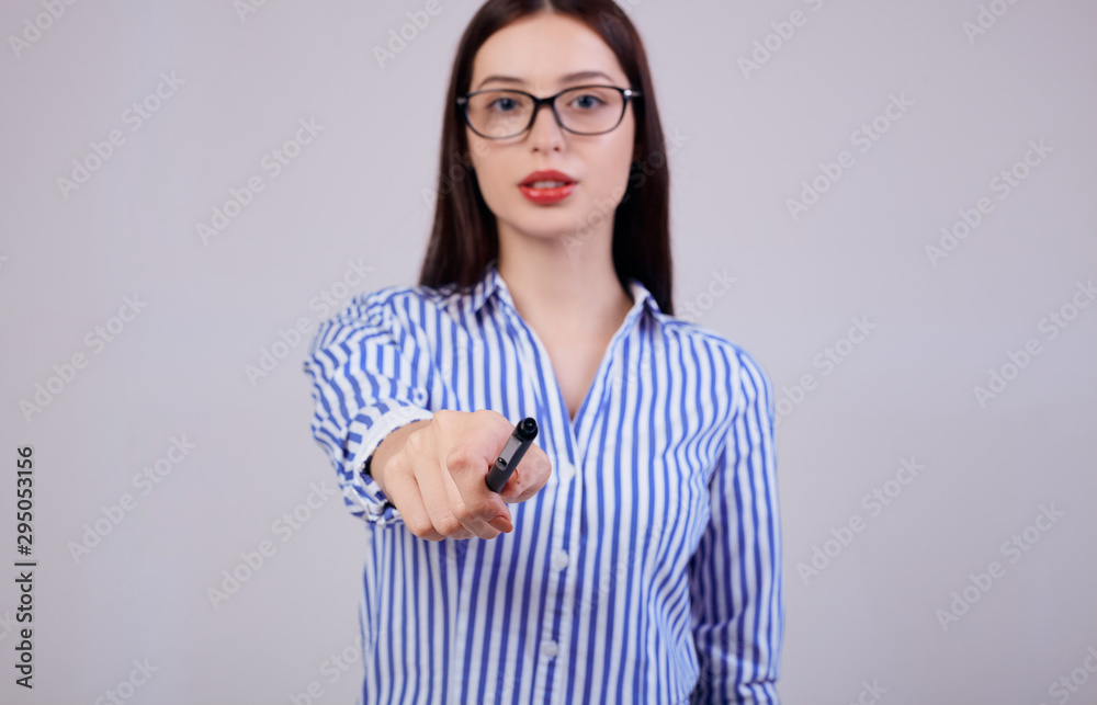 In the background is a pleasant serious young business lady with brown hair and glasses. girl holds a black pen in her hand. In the background is a pleasant serious young business lady with brown hair and glasses. girl holds a black pen in her hand.