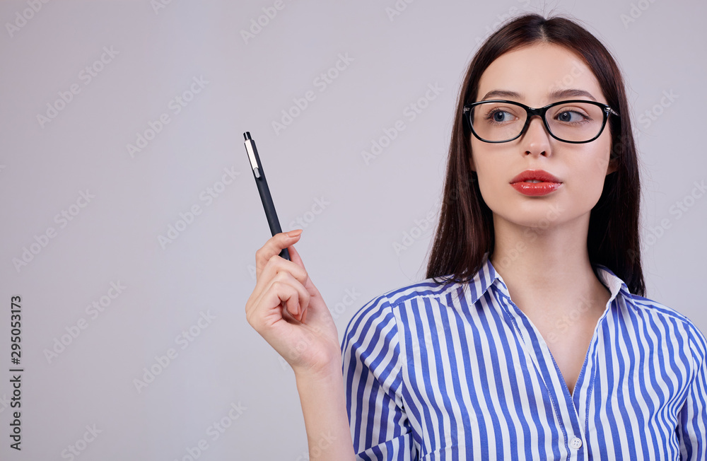 In the background is a pleasant young business woman with brown hair and glasses. girl holds a black pen in her hand and looks at side In the background is a pleasant young business woman with brown hair and glasses. girl holds a black pen in her hand and looks at side