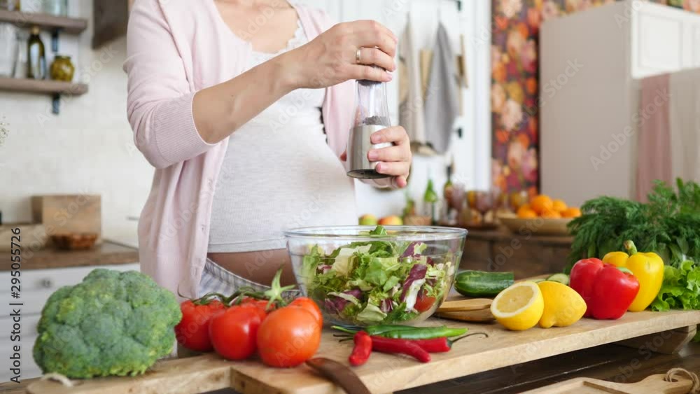 Healthy Pregnancy Concept. Pregnant Female Cooking Salad, Adding Salt And Pepper. Healthy Pregnancy Concept. Pregnant Female Cooking Salad, Adding Salt And Pepper.