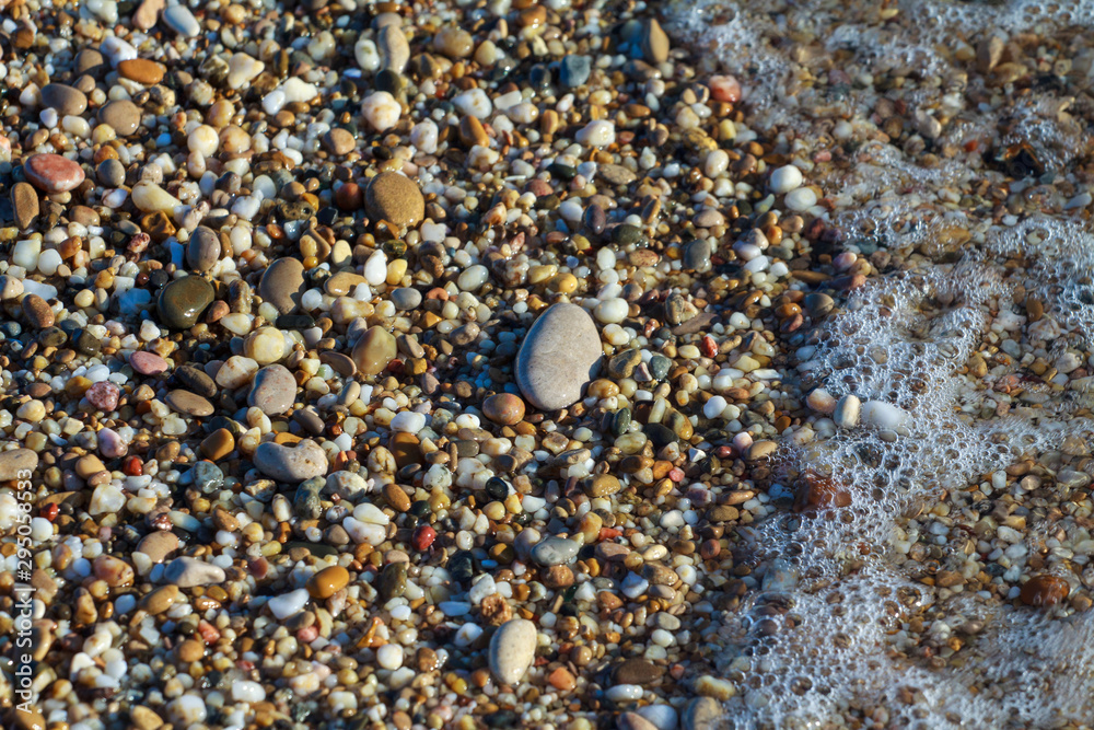 sea pebbles colored granite on the beach background stones. The shore of the beach with sand and pebbles washed by the waves of the sea. sea pebbles colored granite on the beach background stones. The shore of the beach with sand and pebbles washed by the waves of the sea.