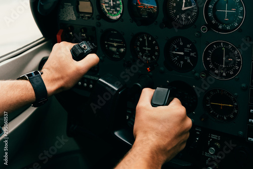 partial view of pilot in wristwatch holding helm in plane