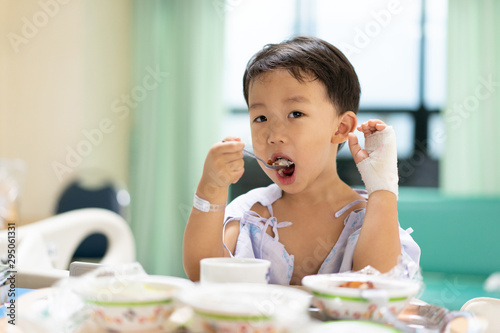 A patient boy is eatting food while he sick in the hospital.