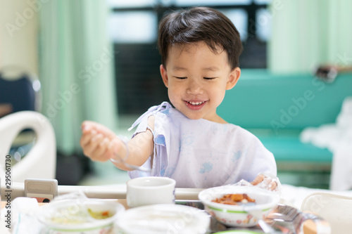 A patient boy is eatting food while he sick in the hospital.